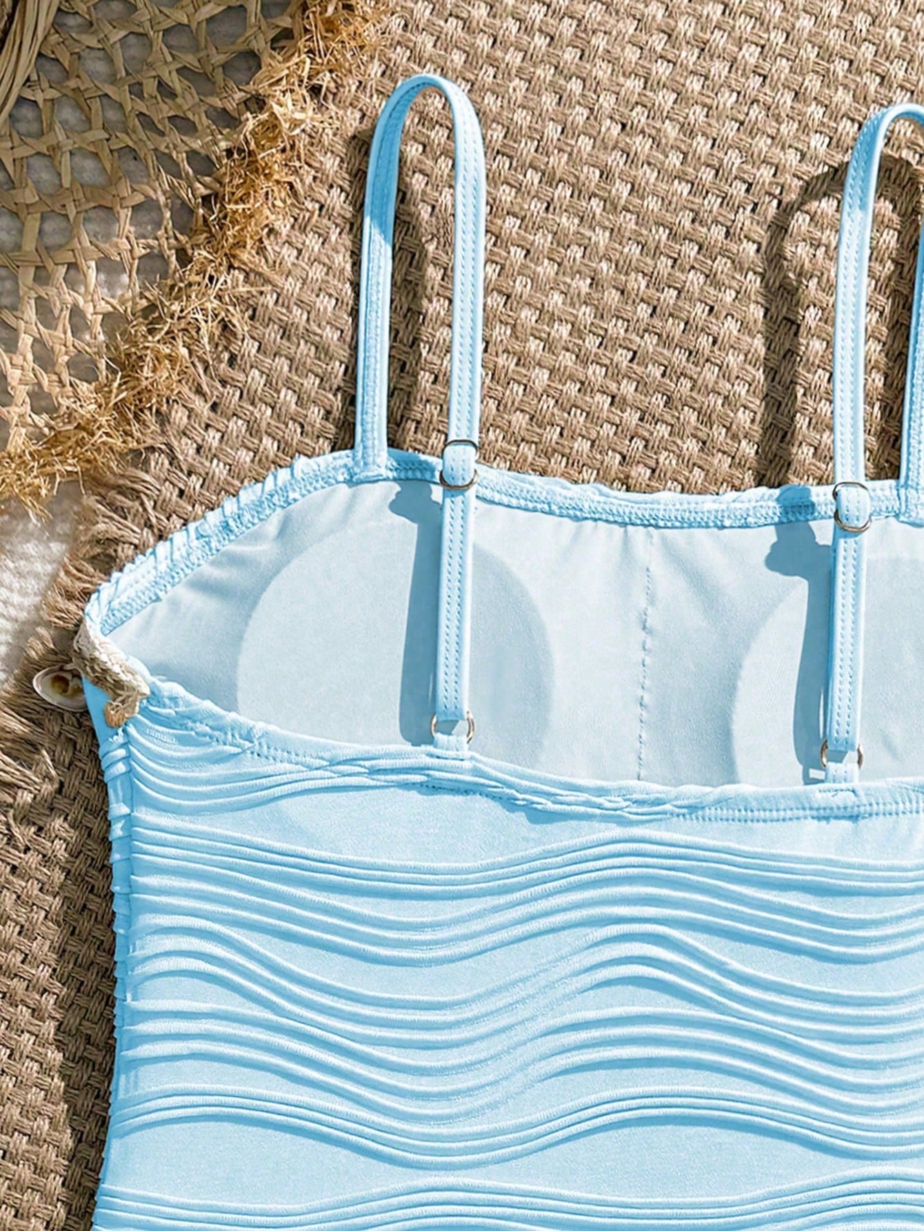 Blue girls one-piece swimsuit with spaghetti straps, textured plain fabric, shell-inspired detail, and matching skirt bottom for beach or pool vacation wear.