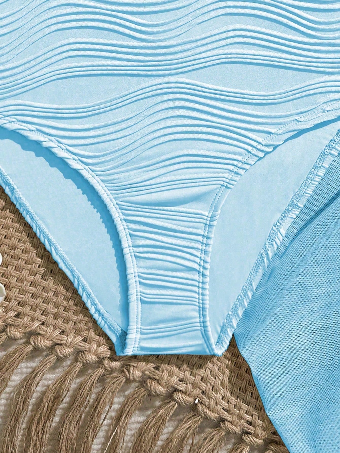 Blue girls one-piece swimsuit with spaghetti straps, textured plain fabric, shell-inspired detail, and matching skirt bottom for beach or pool vacation wear.