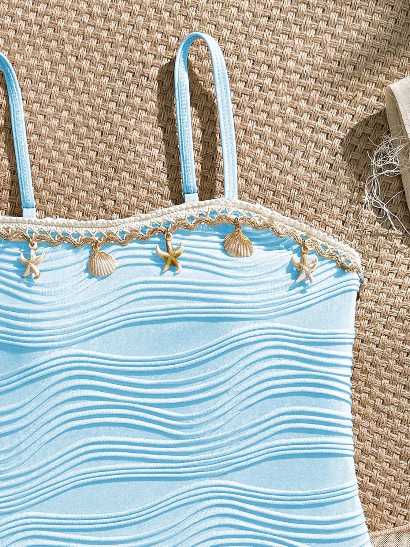 Blue girls one-piece swimsuit with spaghetti straps, textured plain fabric, shell-inspired detail, and matching skirt bottom for beach or pool vacation wear.