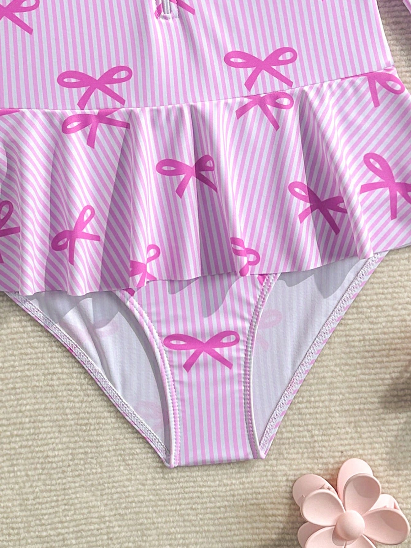 Purple tween girls one-piece swimsuit with graphic striped print, ruffle detail, round neck, and zipper closure for swimming and vacation wear