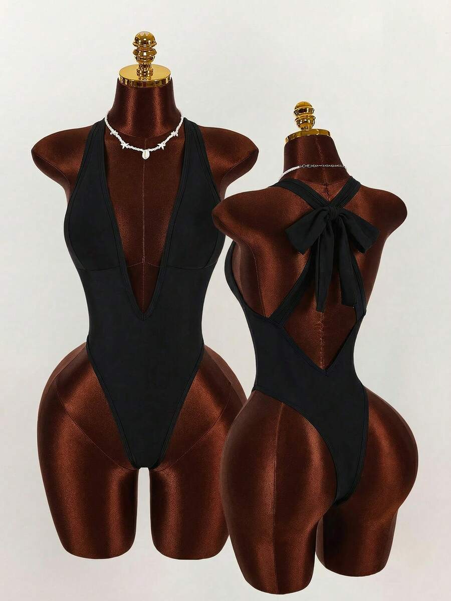 Women's elegant black one-piece swimsuit featuring a deep V-neck line, backless design, zipper detail, and high cut silhouette.
