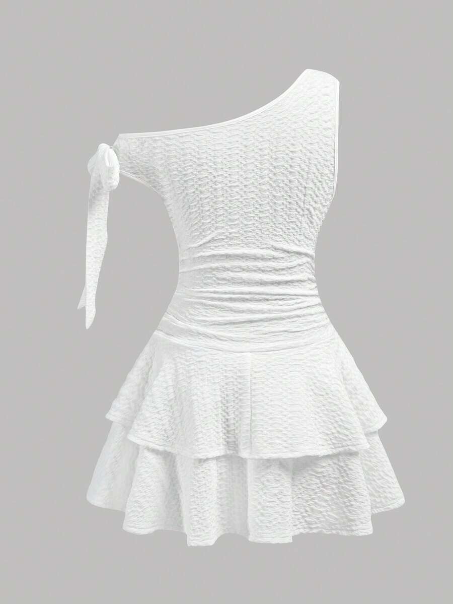 Tween girl wearing an apricot asymmetrical tiered sleeveless party dress with an A-line silhouette.