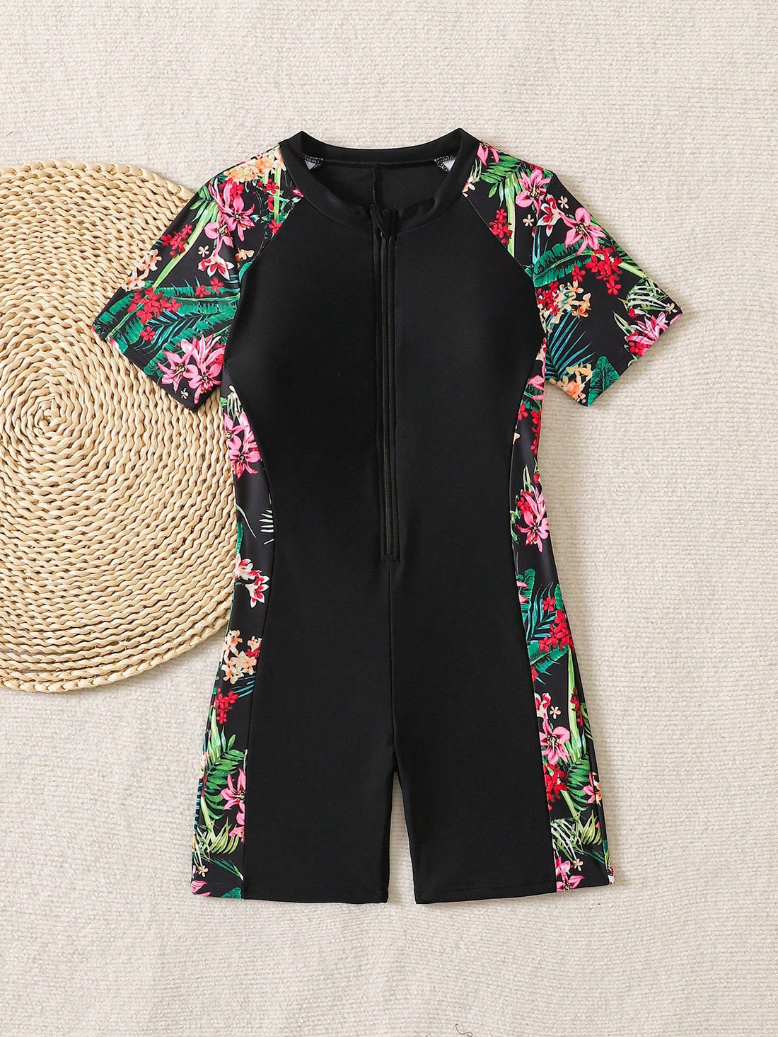 Black and white one-piece rashguard swimsuit for tween girls with short sleeves, high neck, zipper detail, fitted shape, and shorts-style bottom.