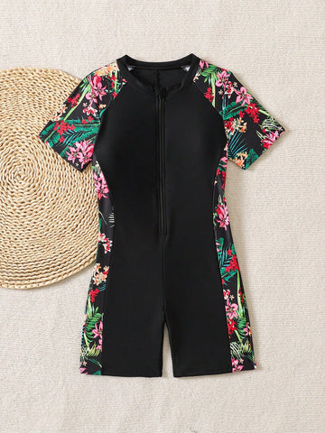 Black and white one-piece rashguard swimsuit for tween girls with short sleeves, high neck, zipper detail, fitted shape, and shorts-style bottom.
