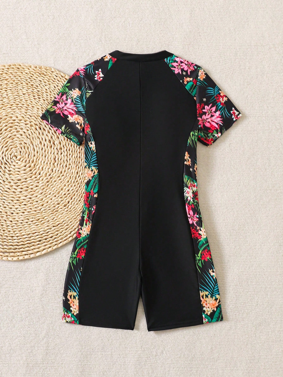 Black and white one-piece rashguard swimsuit for tween girls with short sleeves, high neck, zipper detail, fitted shape, and shorts-style bottom.