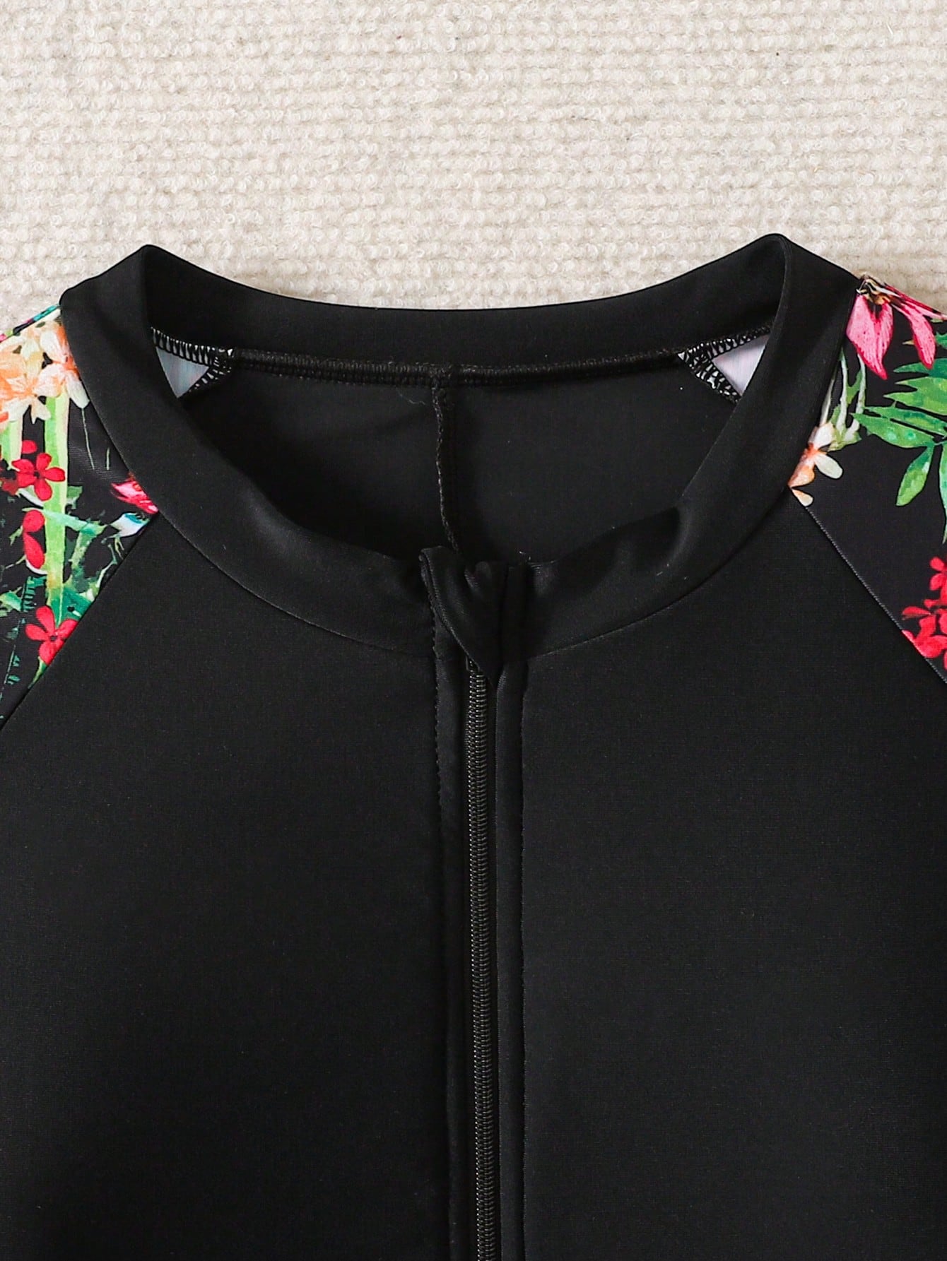 Black and white one-piece rashguard swimsuit for tween girls with short sleeves, high neck, zipper detail, fitted shape, and shorts-style bottom.