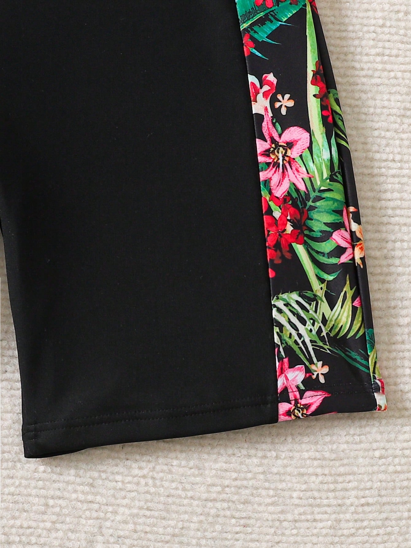 Black and white one-piece rashguard swimsuit for tween girls with short sleeves, high neck, zipper detail, fitted shape, and shorts-style bottom.