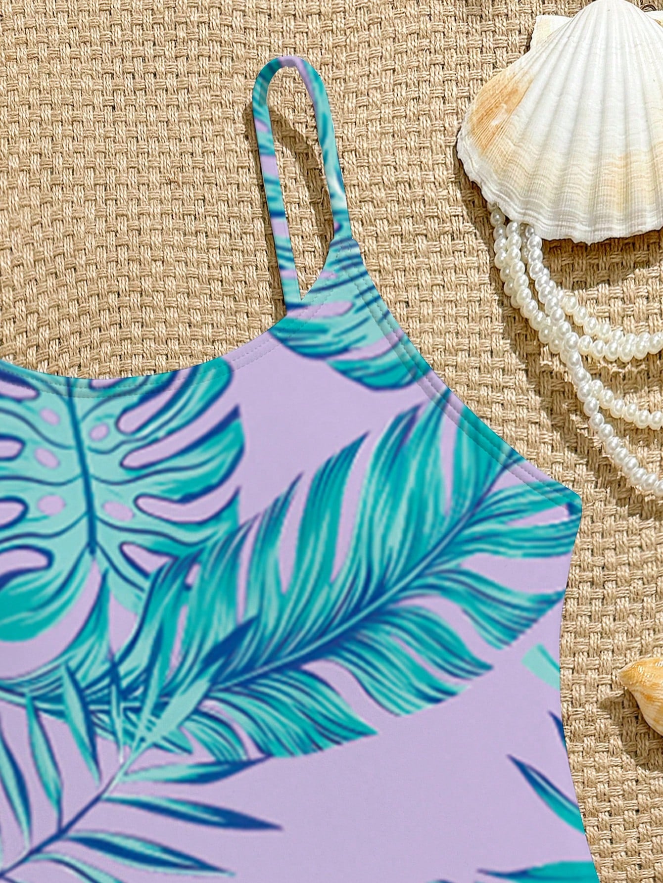 Tween girls one-piece swimsuit with a floral plant print, spaghetti straps, and a mid-waist fit in black.