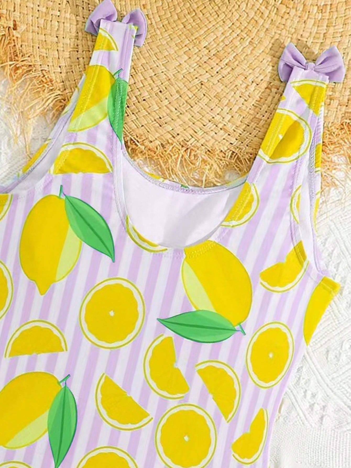 Tween girls purple one-piece swimsuit with lemon stripe pattern, spaghetti straps, ruffle detail, bow design, scoop neckline, and fitted swimwear shape