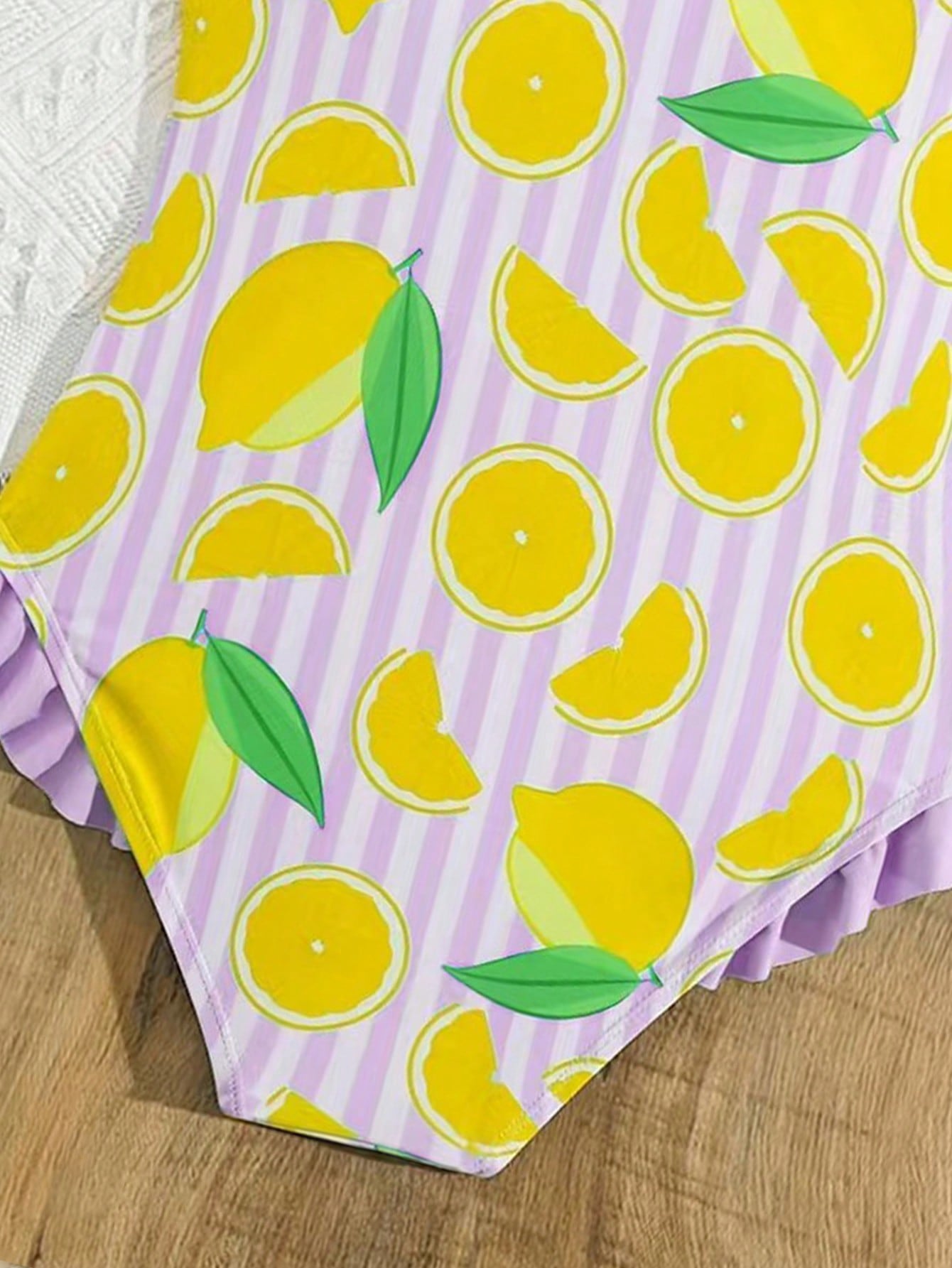 Tween girls purple one-piece swimsuit with lemon stripe pattern, spaghetti straps, ruffle detail, bow design, scoop neckline, and fitted swimwear shape