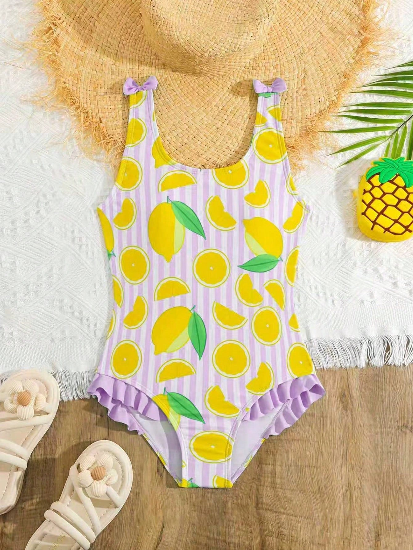 Tween girls purple one-piece swimsuit with lemon stripe pattern, spaghetti straps, ruffle detail, bow design, scoop neckline, and fitted swimwear shape