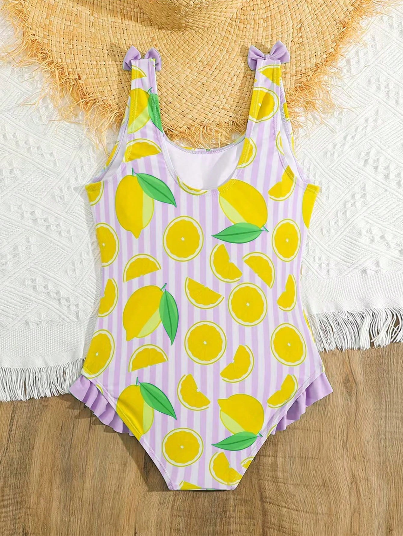 Tween girls purple one-piece swimsuit with lemon stripe pattern, spaghetti straps, ruffle detail, bow design, scoop neckline, and fitted swimwear shape