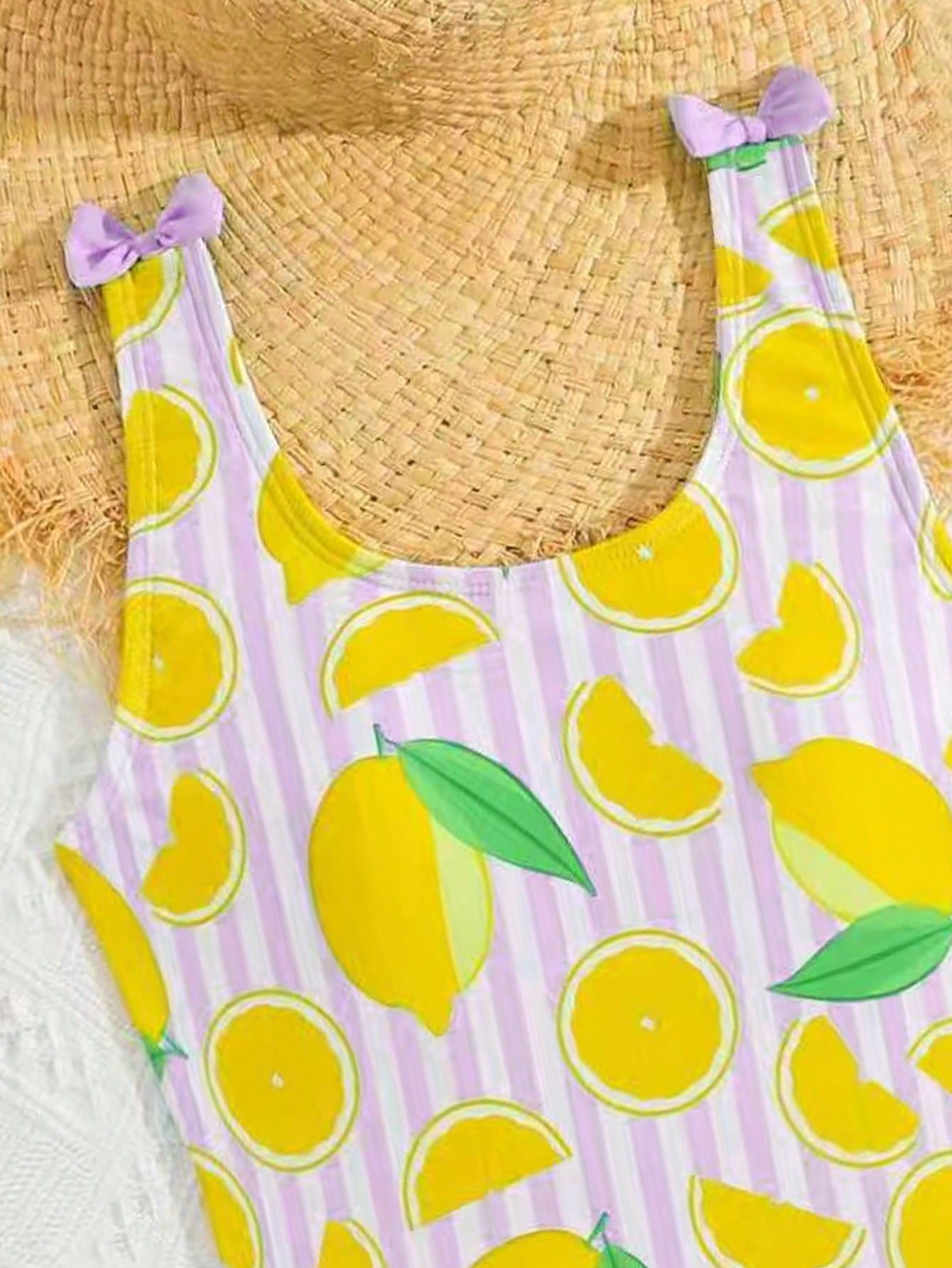 Tween girls purple one-piece swimsuit with lemon stripe pattern, spaghetti straps, ruffle detail, bow design, scoop neckline, and fitted swimwear shape