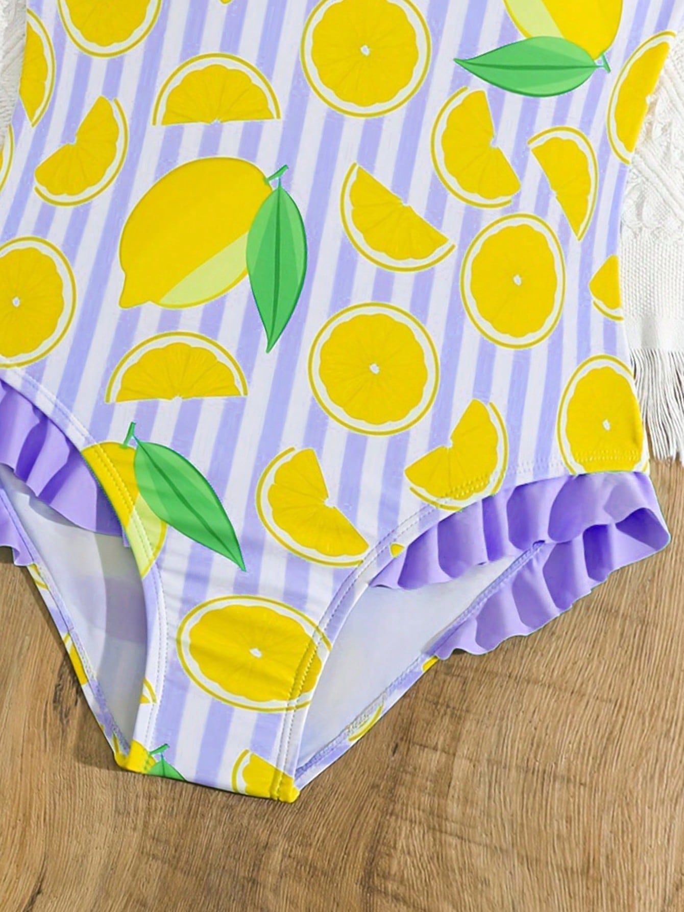 Tween girls purple one-piece swimsuit with lemon stripe pattern, spaghetti straps, ruffle detail, bow design, scoop neckline, and fitted swimwear shape