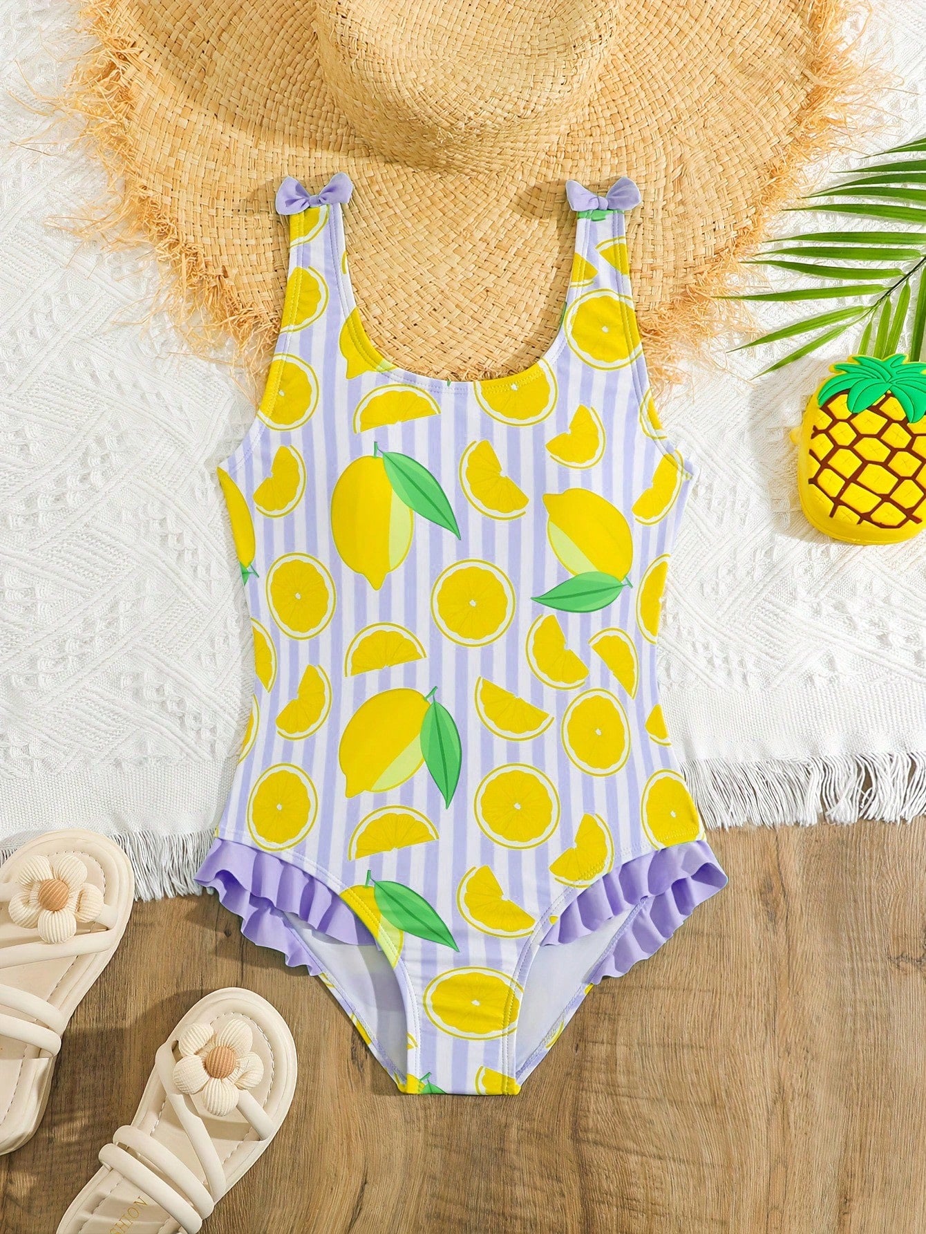 Tween girls purple one-piece swimsuit with lemon stripe pattern, spaghetti straps, ruffle detail, bow design, scoop neckline, and fitted swimwear shape