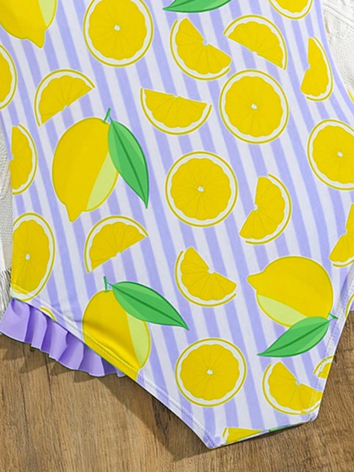 Tween girls purple one-piece swimsuit with lemon stripe pattern, spaghetti straps, ruffle detail, bow design, scoop neckline, and fitted swimwear shape