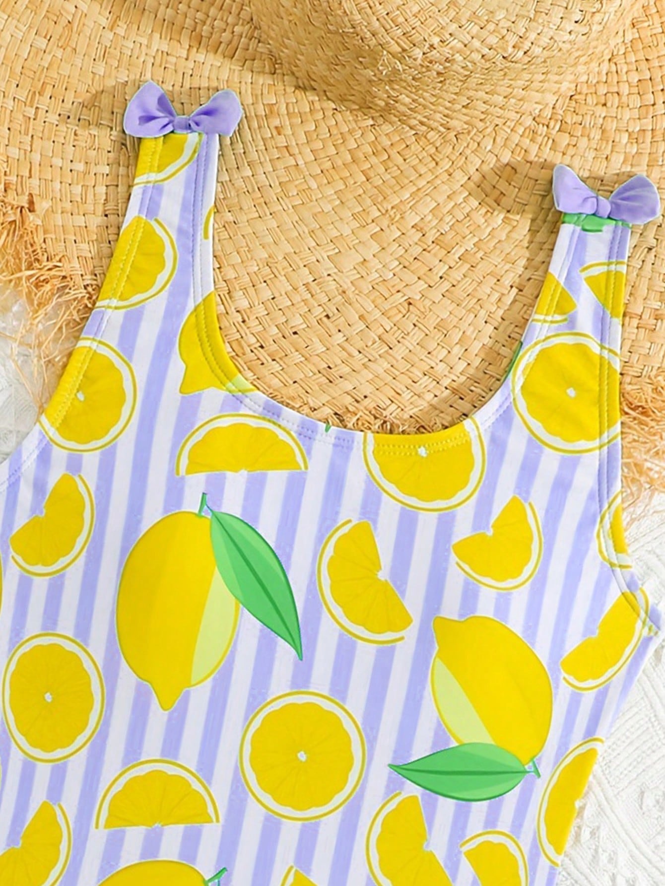 Tween girls purple one-piece swimsuit with lemon stripe pattern, spaghetti straps, ruffle detail, bow design, scoop neckline, and fitted swimwear shape
