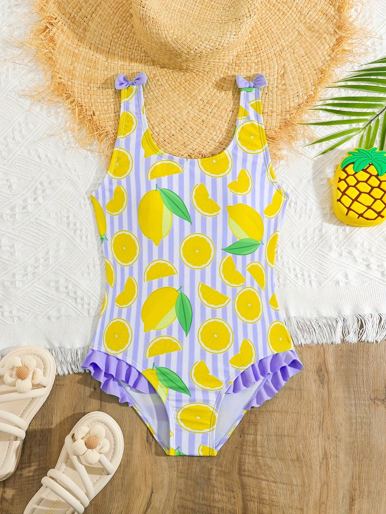 Tween girls purple one-piece swimsuit with lemon stripe pattern, spaghetti straps, ruffle detail, bow design, scoop neckline, and fitted swimwear shape