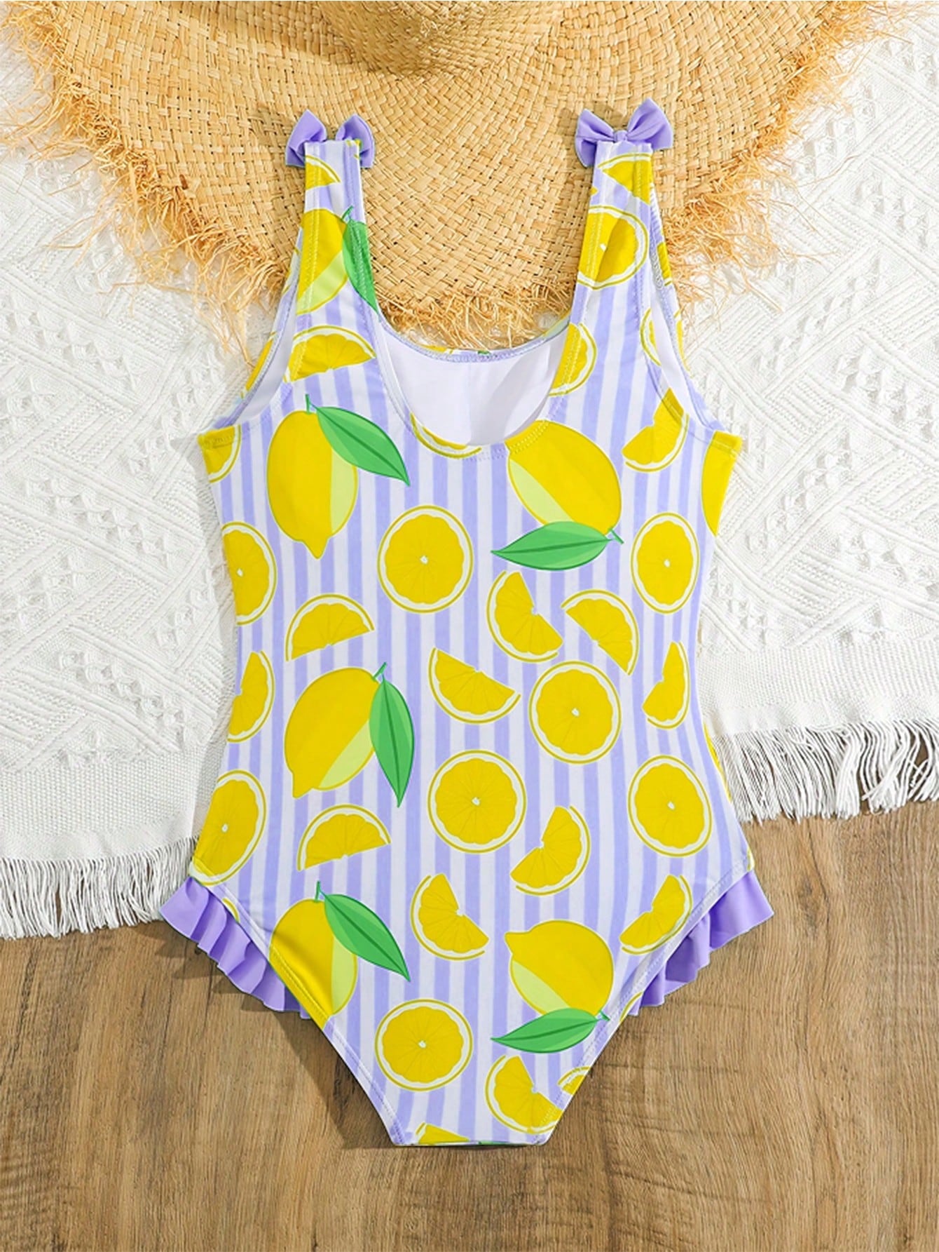 Tween girls purple one-piece swimsuit with lemon stripe pattern, spaghetti straps, ruffle detail, bow design, scoop neckline, and fitted swimwear shape