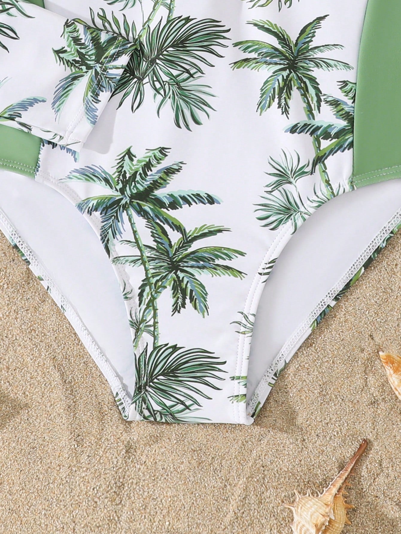 Tween girls one-piece rash guard swimsuit with long sleeves, high neck, front zipper, and ocean shell graphic print in a fitted style for beach, swimming, and vacation wear.
