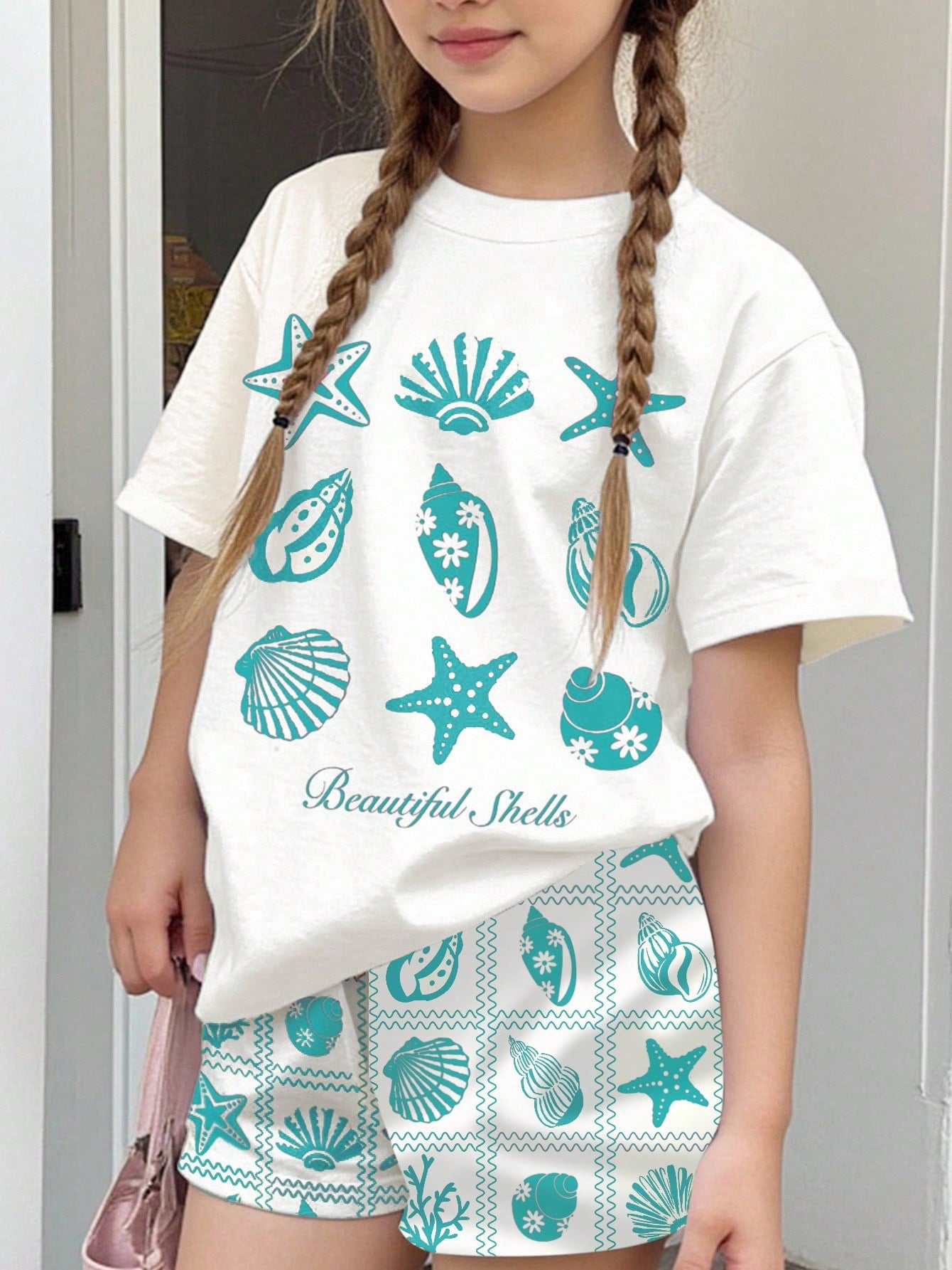 Tween girls 2-piece summer casual outfit featuring a multicolor seashell print short sleeve T-shirt with drop shoulders and matching loose fit shorts with pockets.