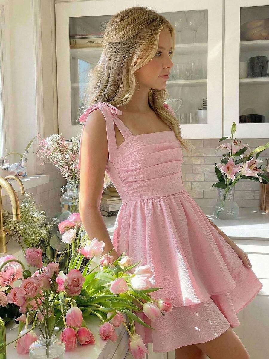 Tween girl wearing a pink tiered off-the-shoulder midi dress with shirred high waist and layered hem