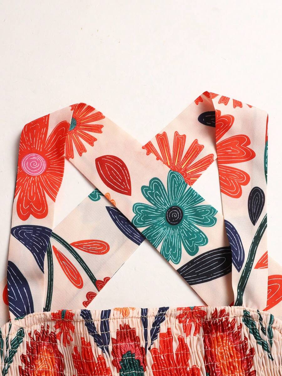 Pink sleeveless tween girls vacation dress with all-over fruit and vegetable print, strap neckline, belted high waist, cut-out detail, and flared ruffle hem.