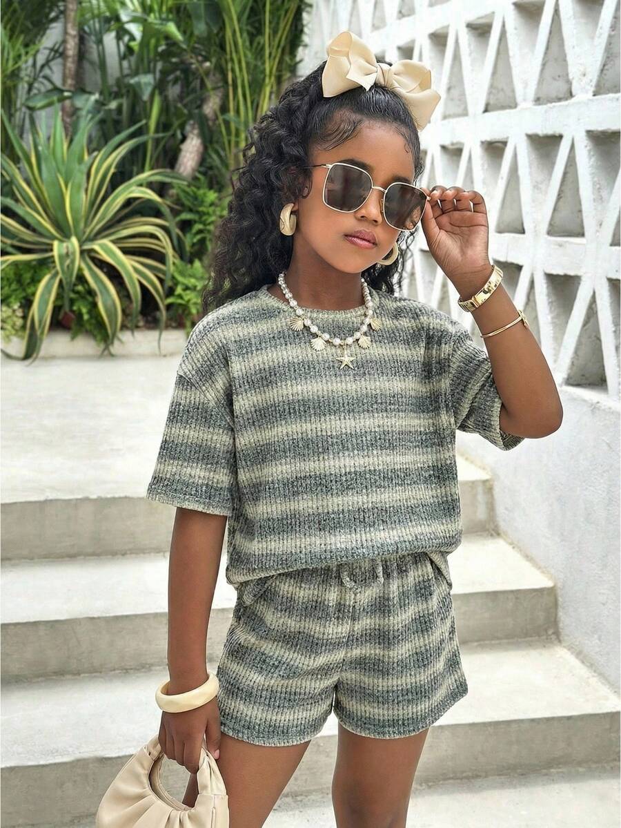 Tween girl wearing a black and white striped drop-shoulder crew neck t-shirt with bow embroidery paired with matching tie-waist shorts.