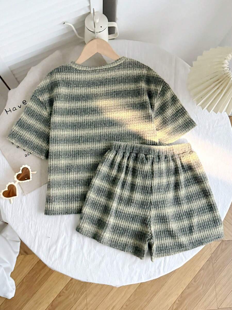 Tween girl wearing a black and white striped drop-shoulder crew neck t-shirt with bow embroidery paired with matching tie-waist shorts.