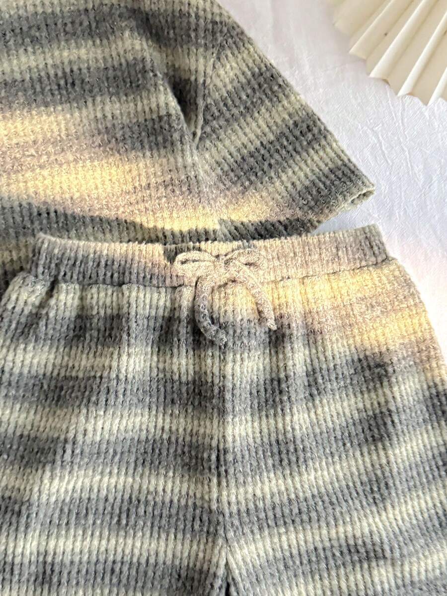 Tween girl wearing a black and white striped drop-shoulder crew neck t-shirt with bow embroidery paired with matching tie-waist shorts.