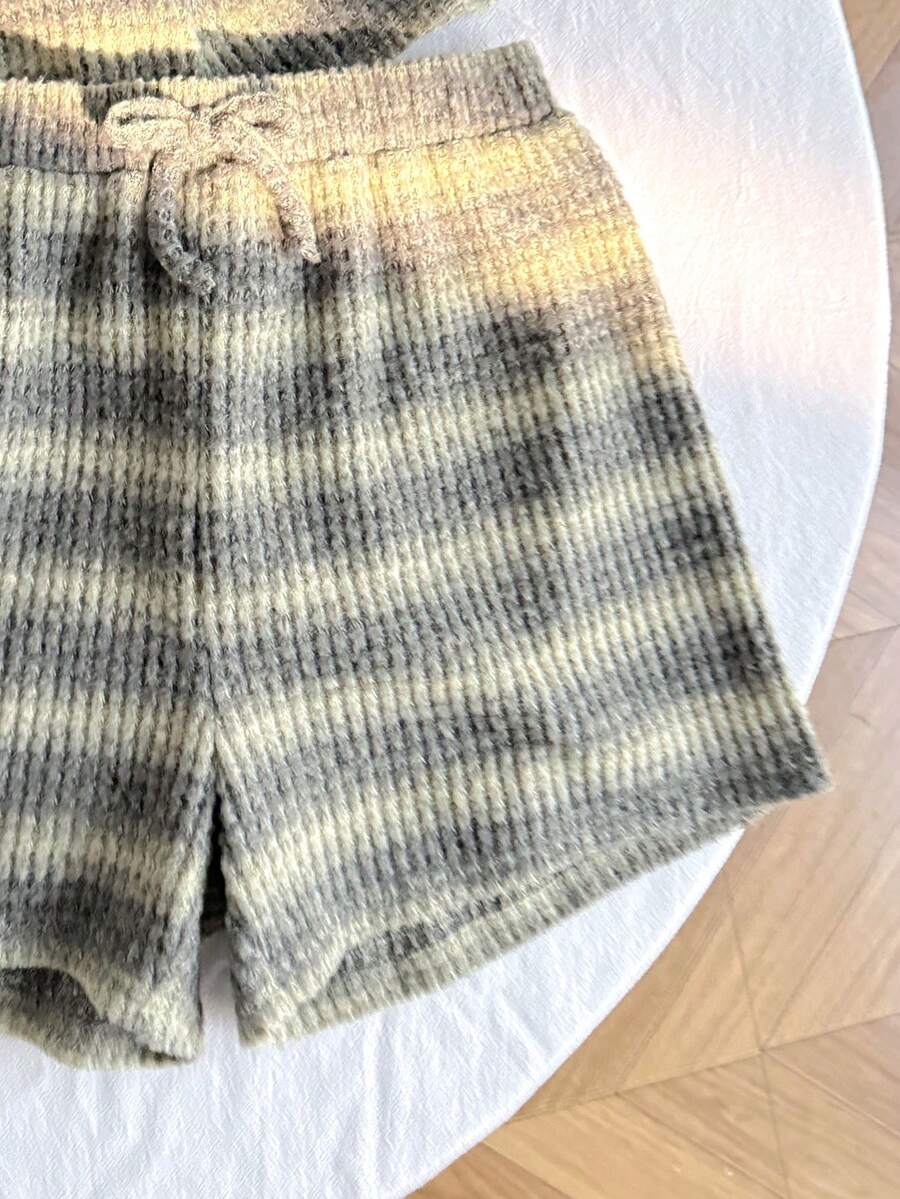 Tween girl wearing a black and white striped drop-shoulder crew neck t-shirt with bow embroidery paired with matching tie-waist shorts.