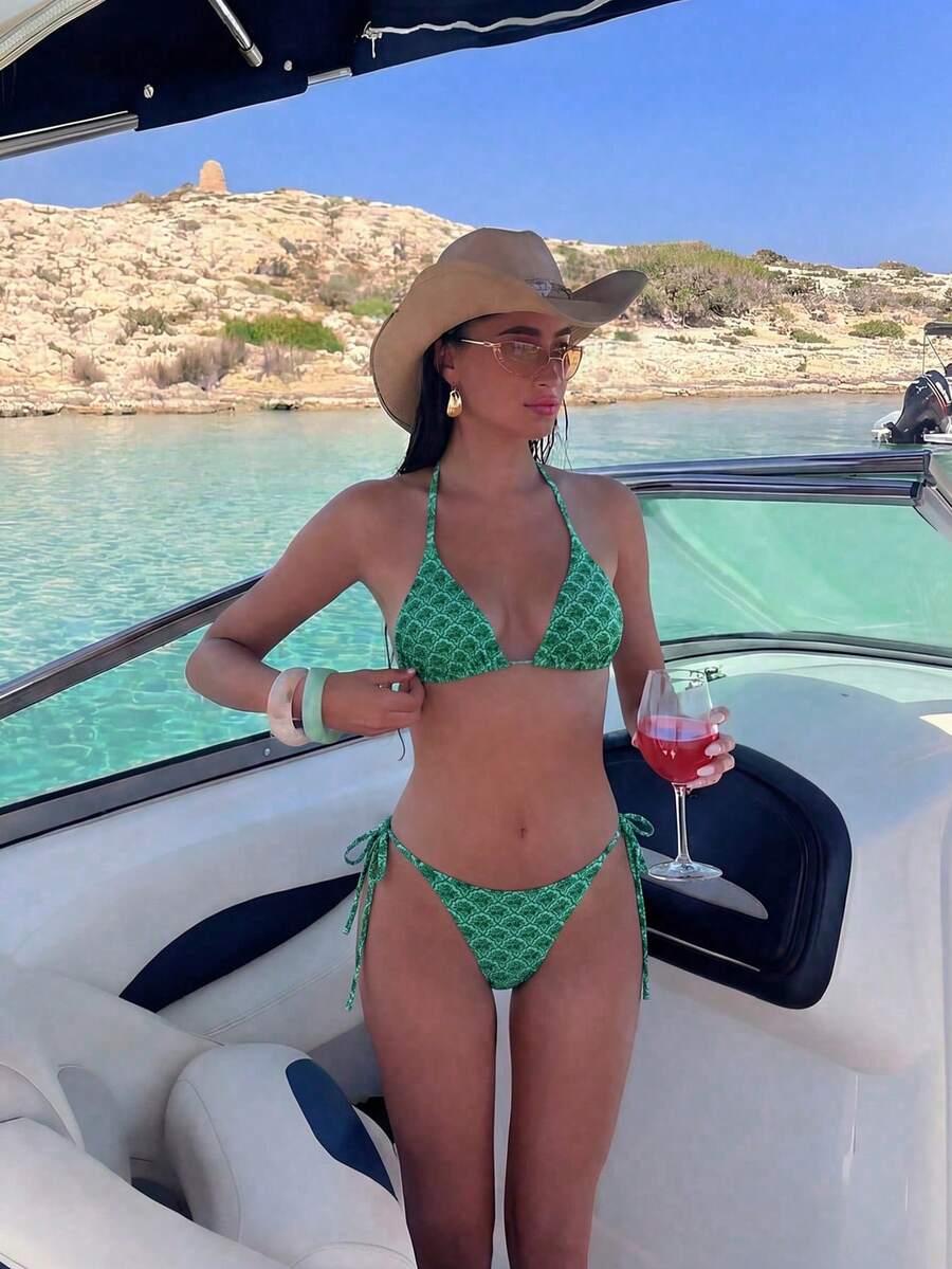 Women's black two-piece bikini set featuring a halter neck with a colorful sun pendant, triangle cups, and high-cut tie-side bottoms.