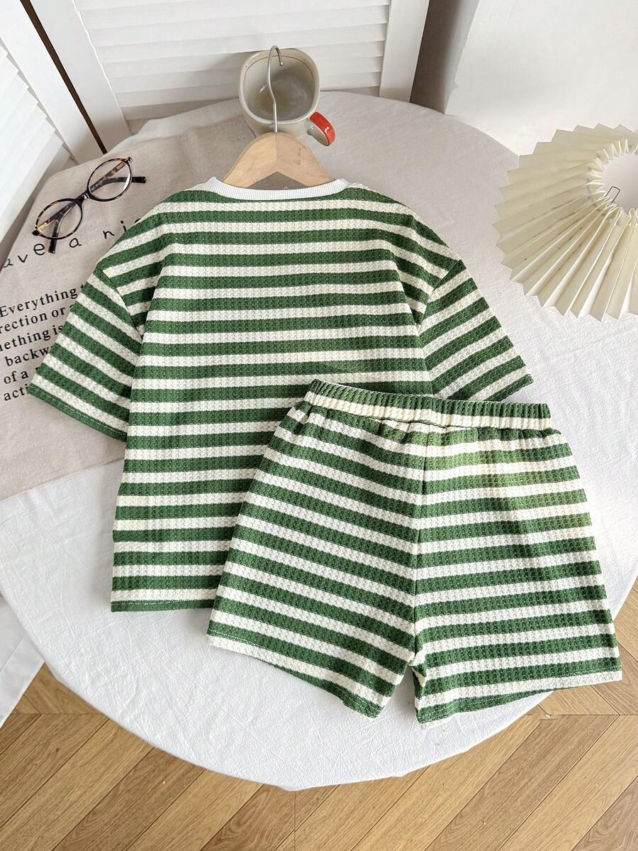 Tween girl wearing a black and white striped drop-shoulder crew neck t-shirt with bow embroidery paired with matching tie-waist shorts.