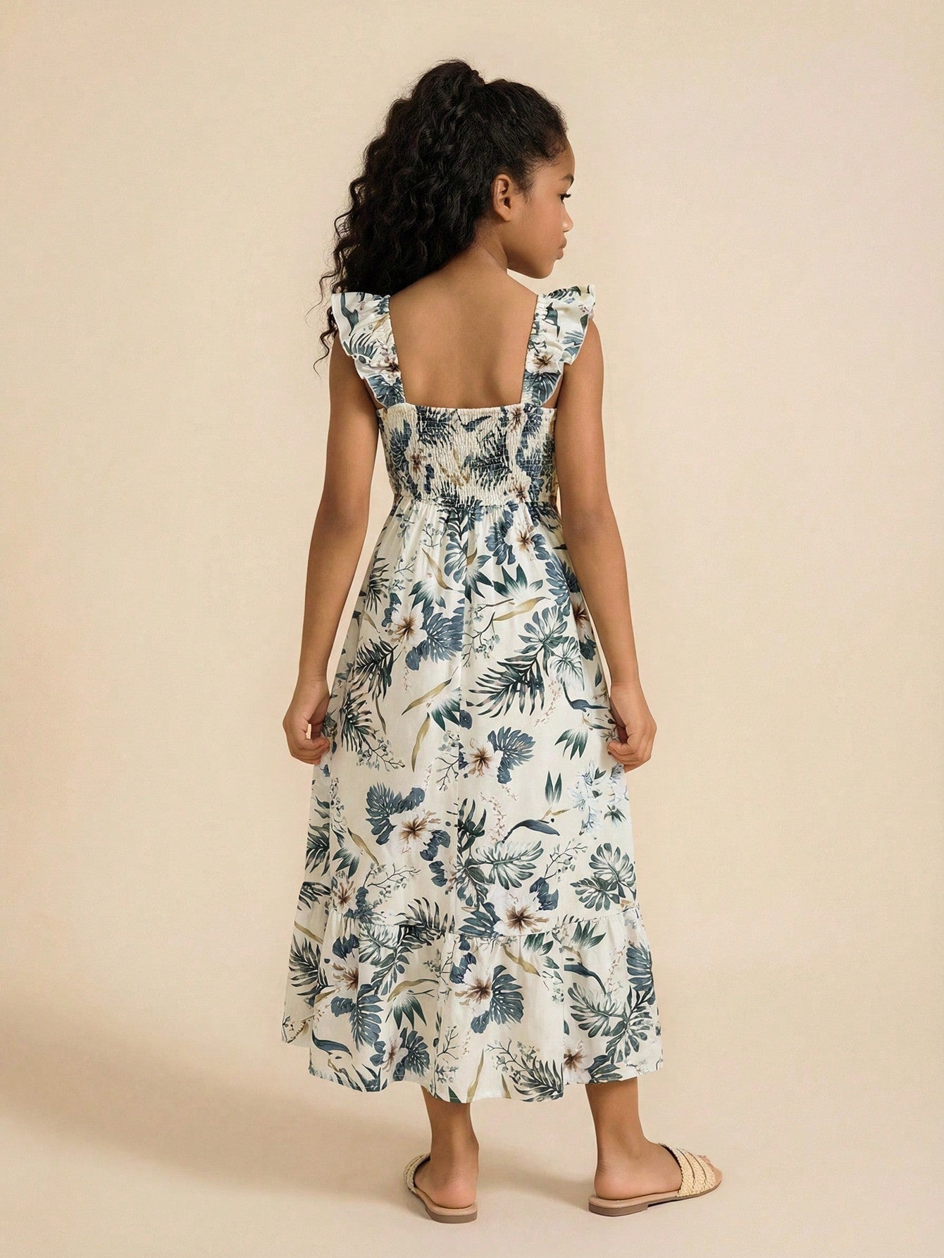 Tween girl multicolor floral vacation dress with square neck, ruffle details, shirred bodice, sleeveless A-line shape, high waist, and flounce hem.