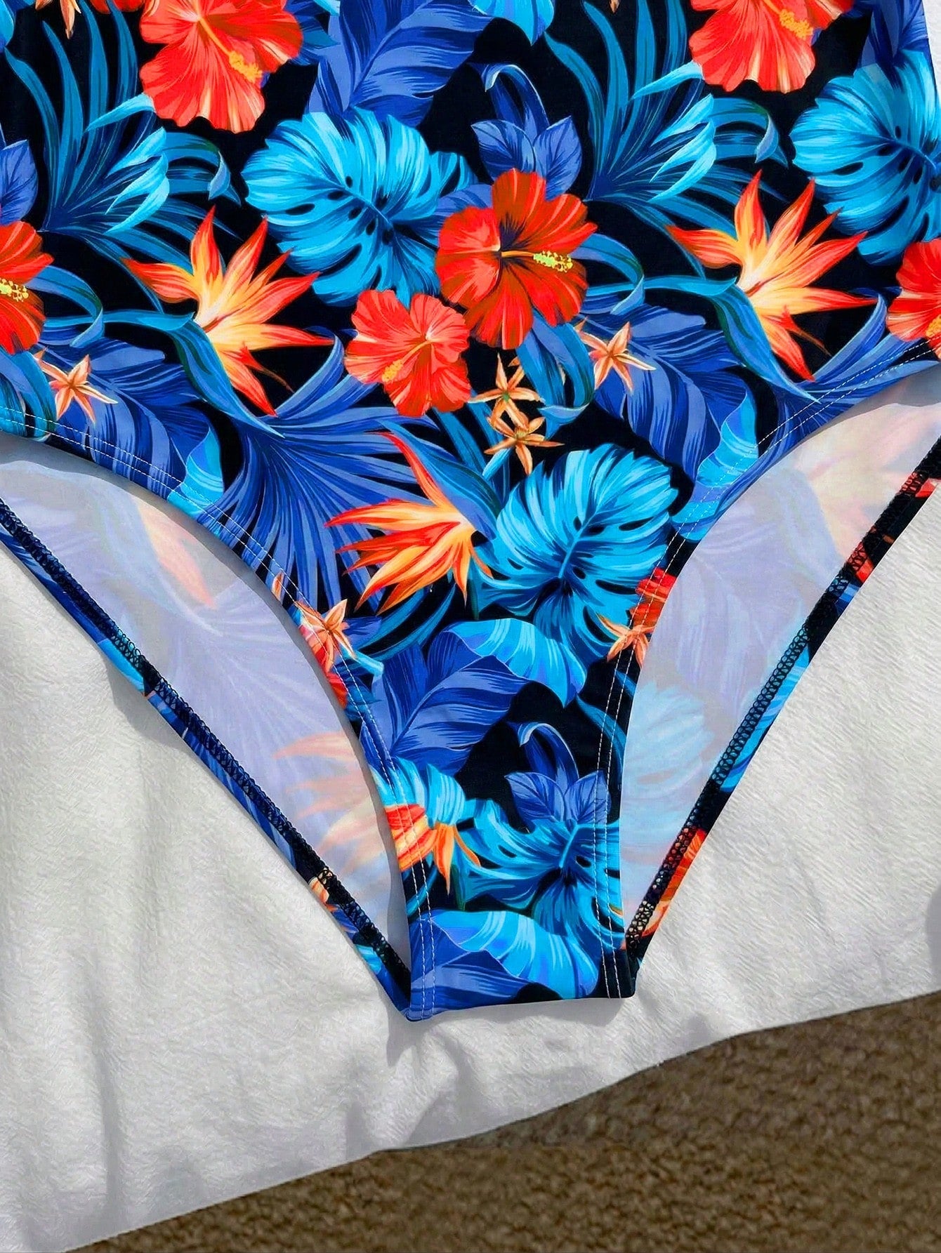 Tween girls one-piece swimsuit with a floral plant print, spaghetti straps, and a mid-waist fit in black.