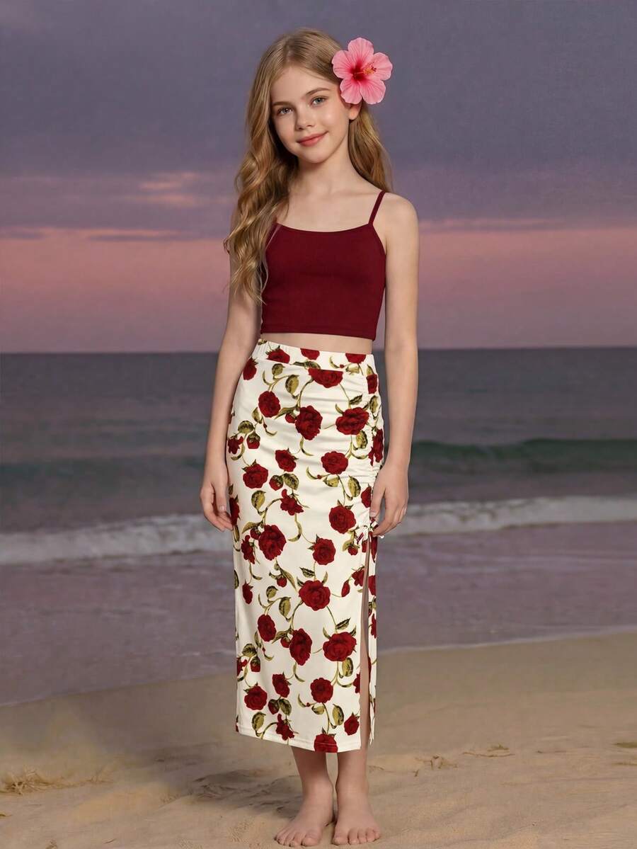 Tween girl wearing a 2-piece set featuring a black rib-knit spaghetti strap camisole top and a ruched leopard print midi skirt.