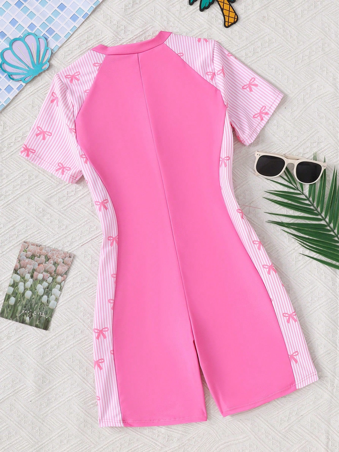 Black and white one-piece rashguard swimsuit for tween girls with short sleeves, high neck, zipper detail, fitted shape, and shorts-style bottom.