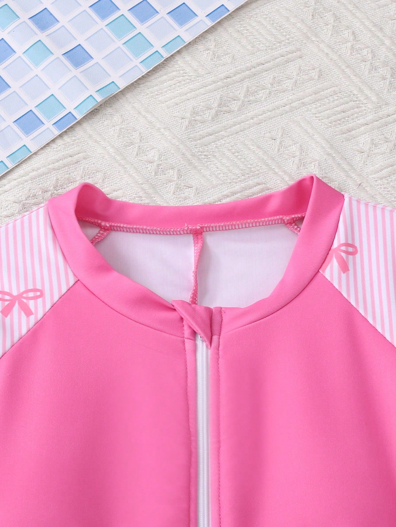 Black and white one-piece rashguard swimsuit for tween girls with short sleeves, high neck, zipper detail, fitted shape, and shorts-style bottom.