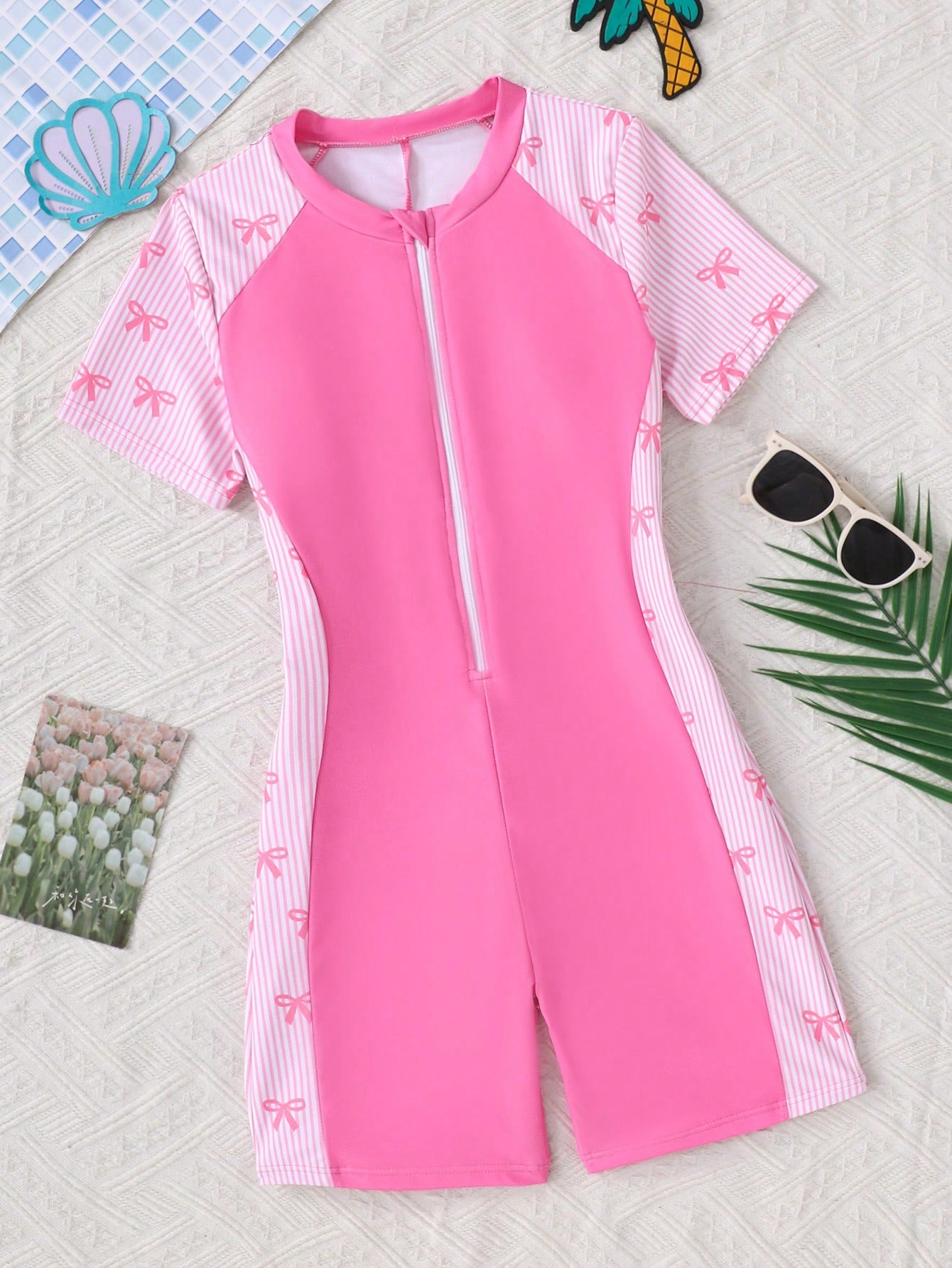 Black and white one-piece rashguard swimsuit for tween girls with short sleeves, high neck, zipper detail, fitted shape, and shorts-style bottom.