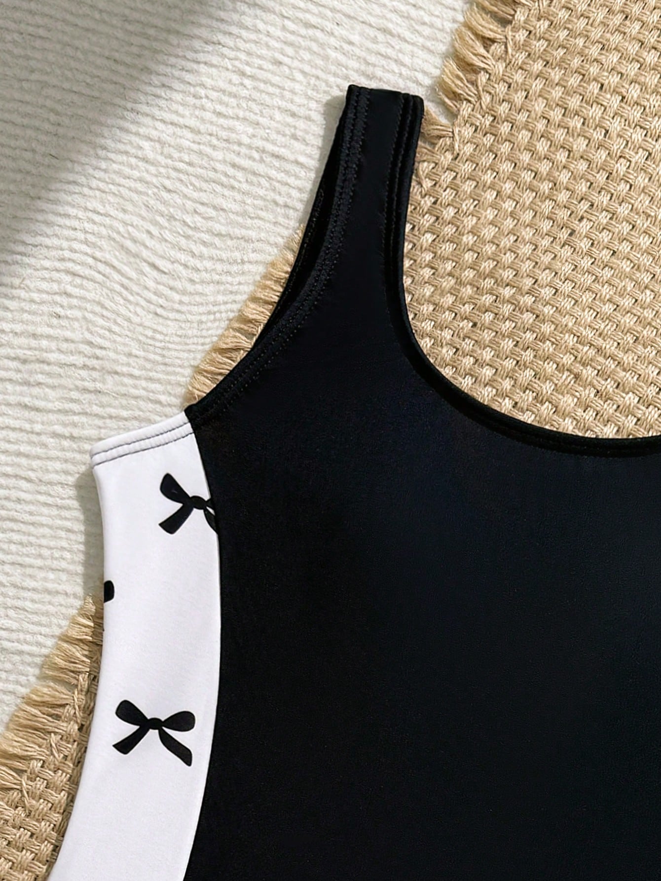 Tween girls 2-piece swimsuit set in black with full floral and plant print, featuring a sleeveless scoop-neck swim top and matching shorts-style bottoms.