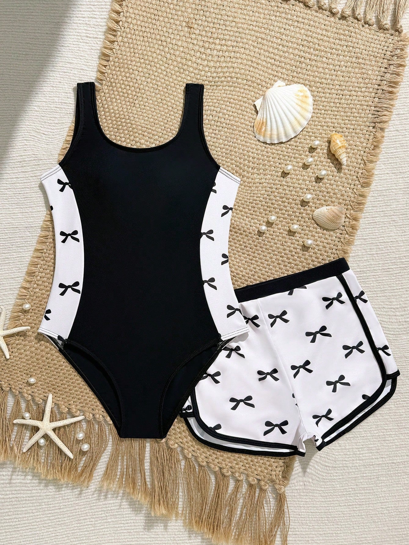Tween girls 2-piece swimsuit set in black with full floral and plant print, featuring a sleeveless scoop-neck swim top and matching shorts-style bottoms.