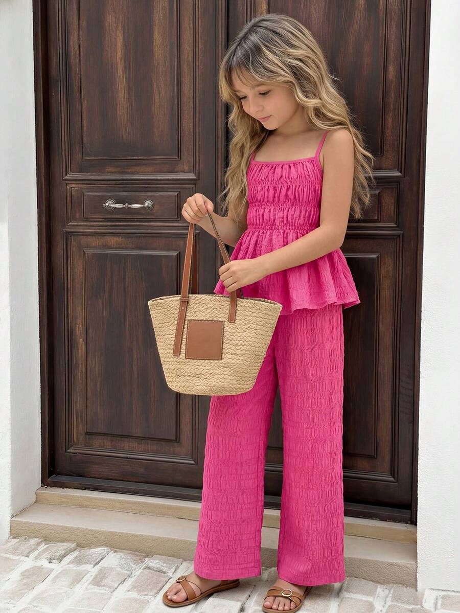 Tween girl wearing an apricot 2-piece outfit set featuring a shirred spaghetti strap short cami top and matching wide-leg long pants.