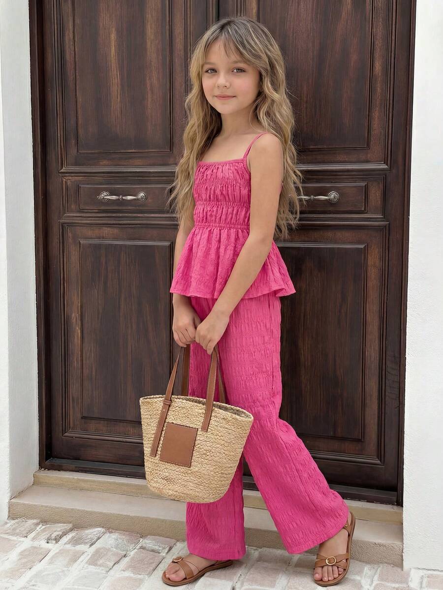 Tween girl wearing an apricot 2-piece outfit set featuring a shirred spaghetti strap short cami top and matching wide-leg long pants.