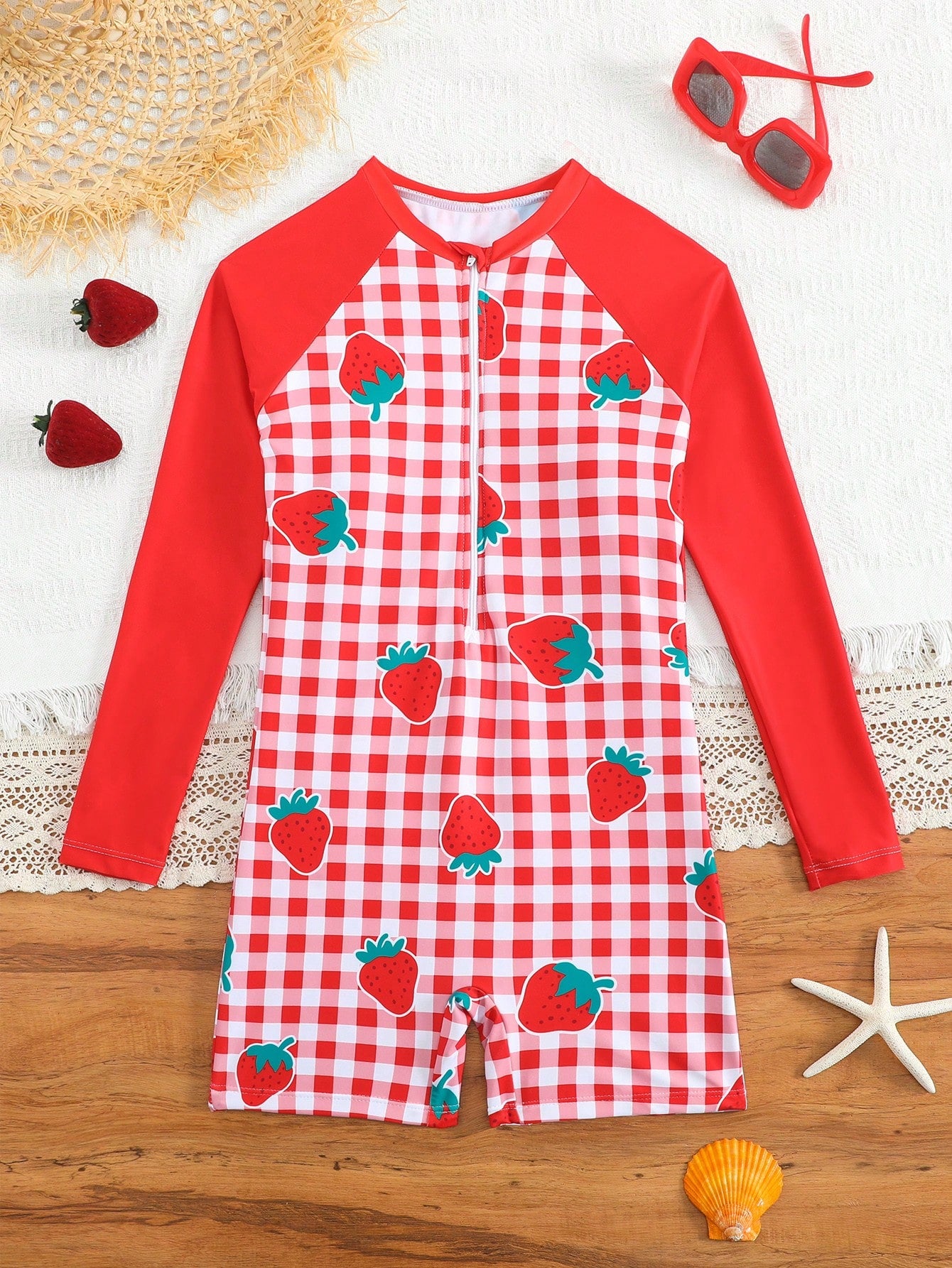 Tween girls one-piece swimsuit featuring a high neck, long sleeves, and shorts bottom, with a back zipper and strawberry plaid digital print on stretch knit fabric. Designed for swimming, vacation, and summer wear.