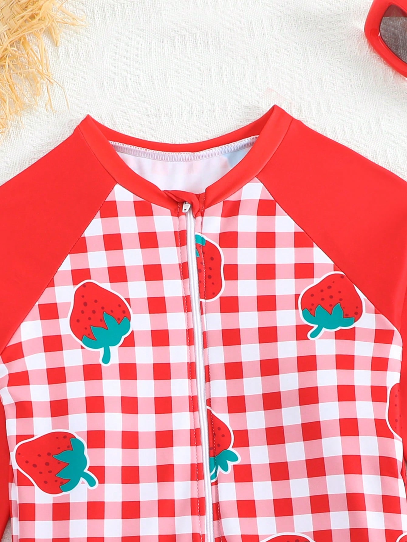 Tween girls one-piece swimsuit featuring a high neck, long sleeves, and shorts bottom, with a back zipper and strawberry plaid digital print on stretch knit fabric. Designed for swimming, vacation, and summer wear.