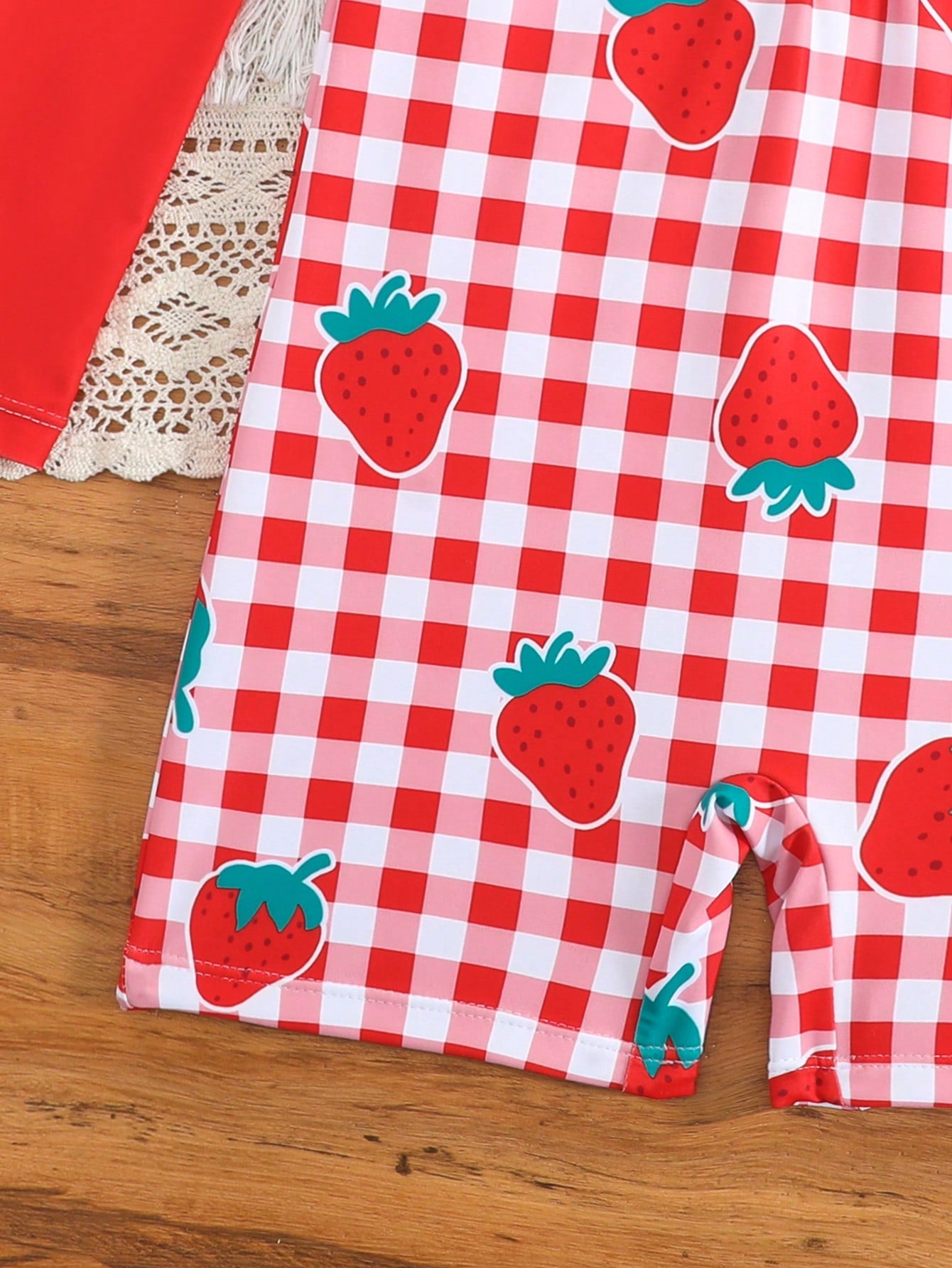 Tween girls one-piece swimsuit featuring a high neck, long sleeves, and shorts bottom, with a back zipper and strawberry plaid digital print on stretch knit fabric. Designed for swimming, vacation, and summer wear.