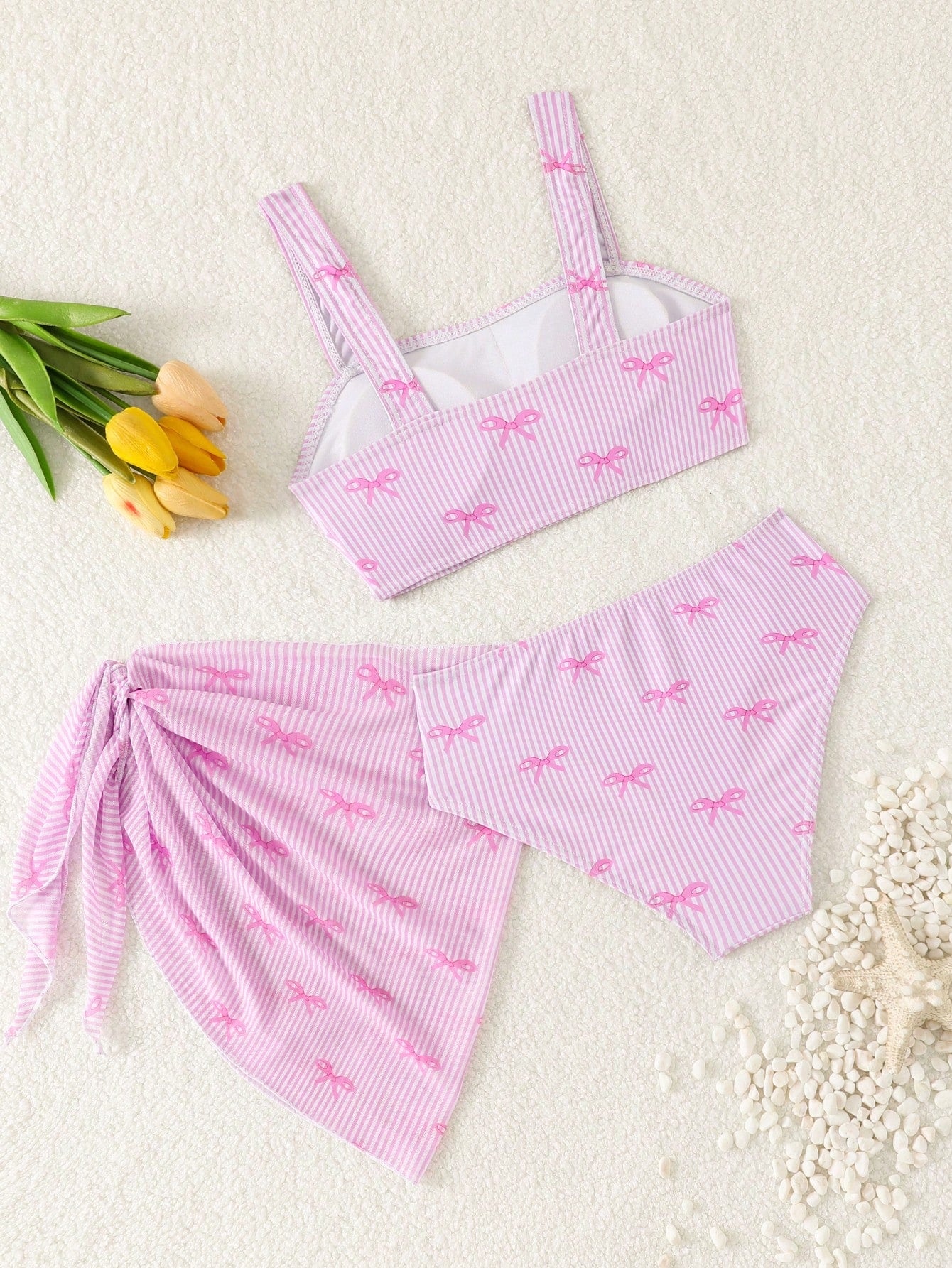 Tween girls three-piece bikini set featuring a bow print bandeau-style top, matching mid-waist bikini bottom, and a sheer mesh cover skirt in a cute beachwear style.