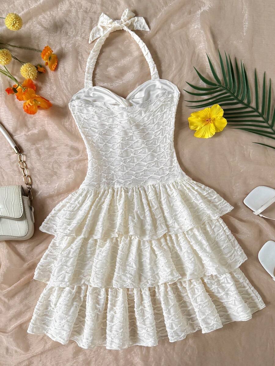 Beige tween girls halter dress with textured jacquard fabric, plant pattern, shirred detail, zipper closure, and layered tiered ruffle hem for vacation wear