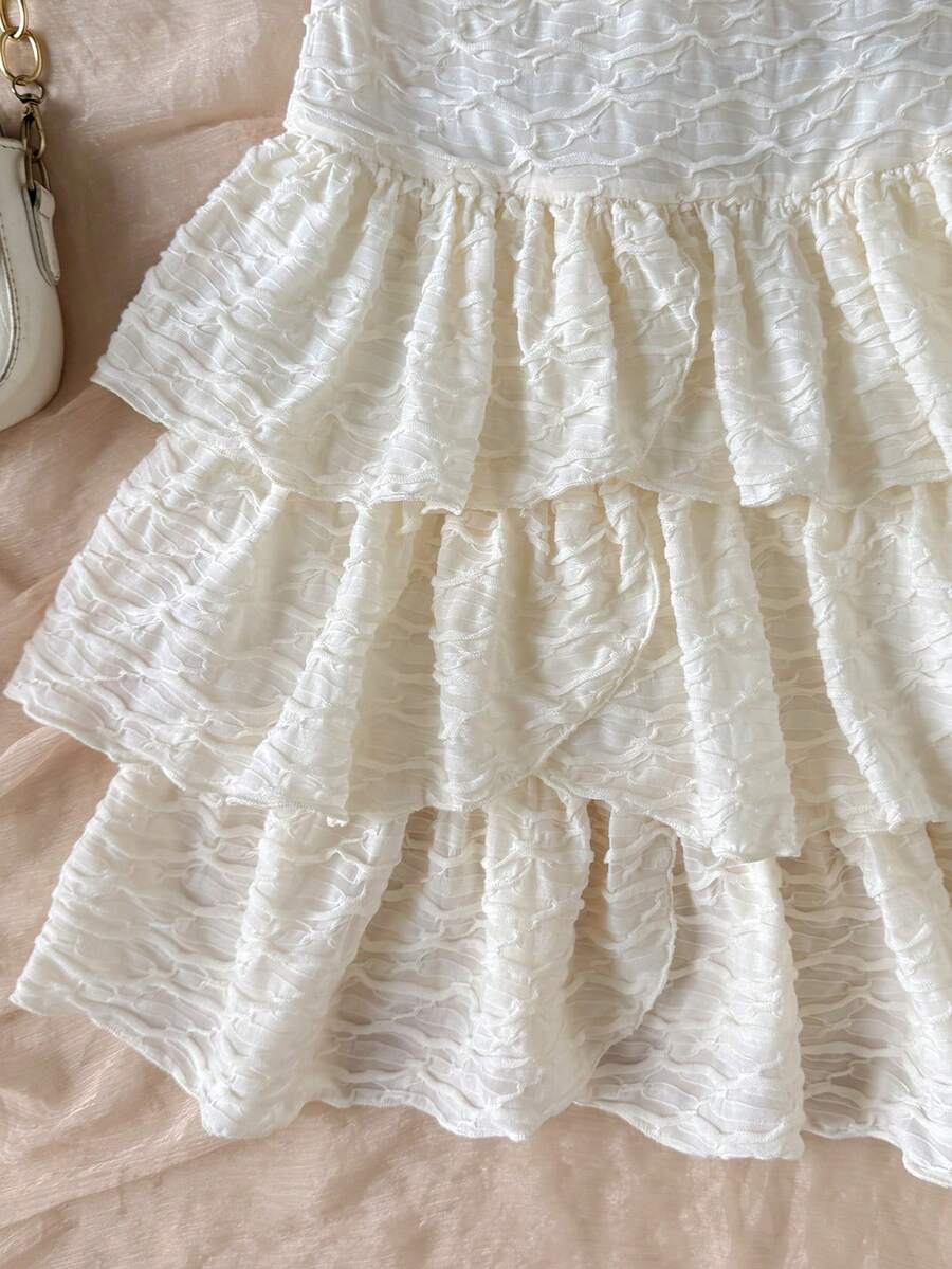 Beige tween girls halter dress with textured jacquard fabric, plant pattern, shirred detail, zipper closure, and layered tiered ruffle hem for vacation wear