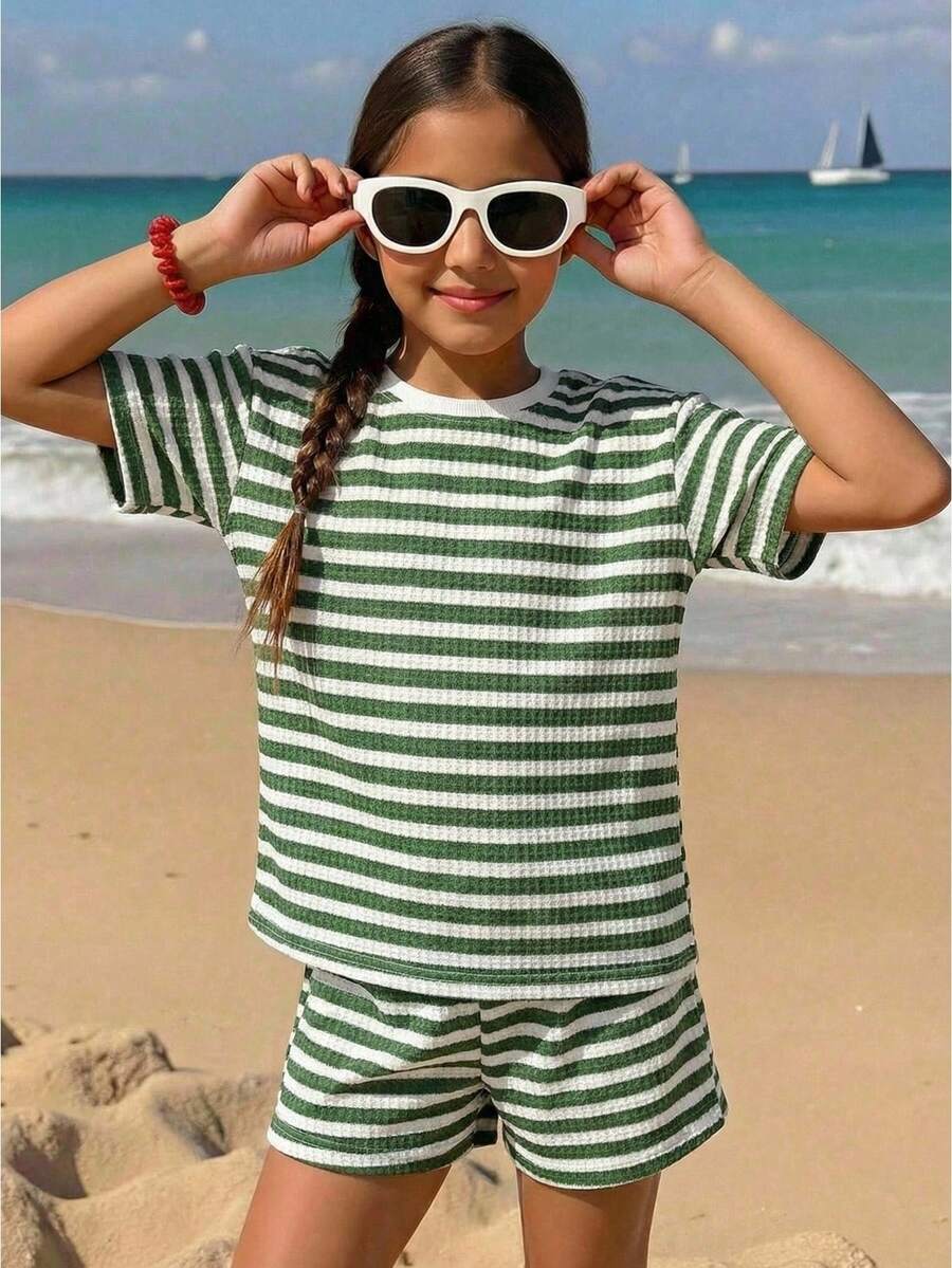 Tween girl wearing a black and white striped drop-shoulder crew neck t-shirt with bow embroidery paired with matching tie-waist shorts.